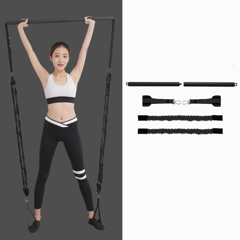 Woman holding a black Pilates bar overhead, beside the two-piece bar, foot straps and two resistance cords