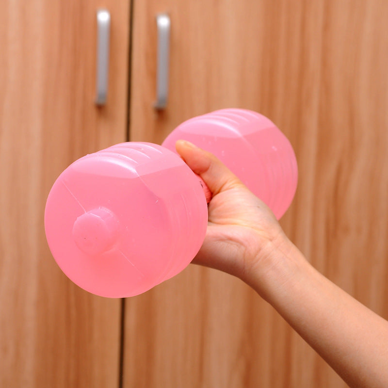 Hand holding a pink water-fill dumbbell in front of a wooden cabinet