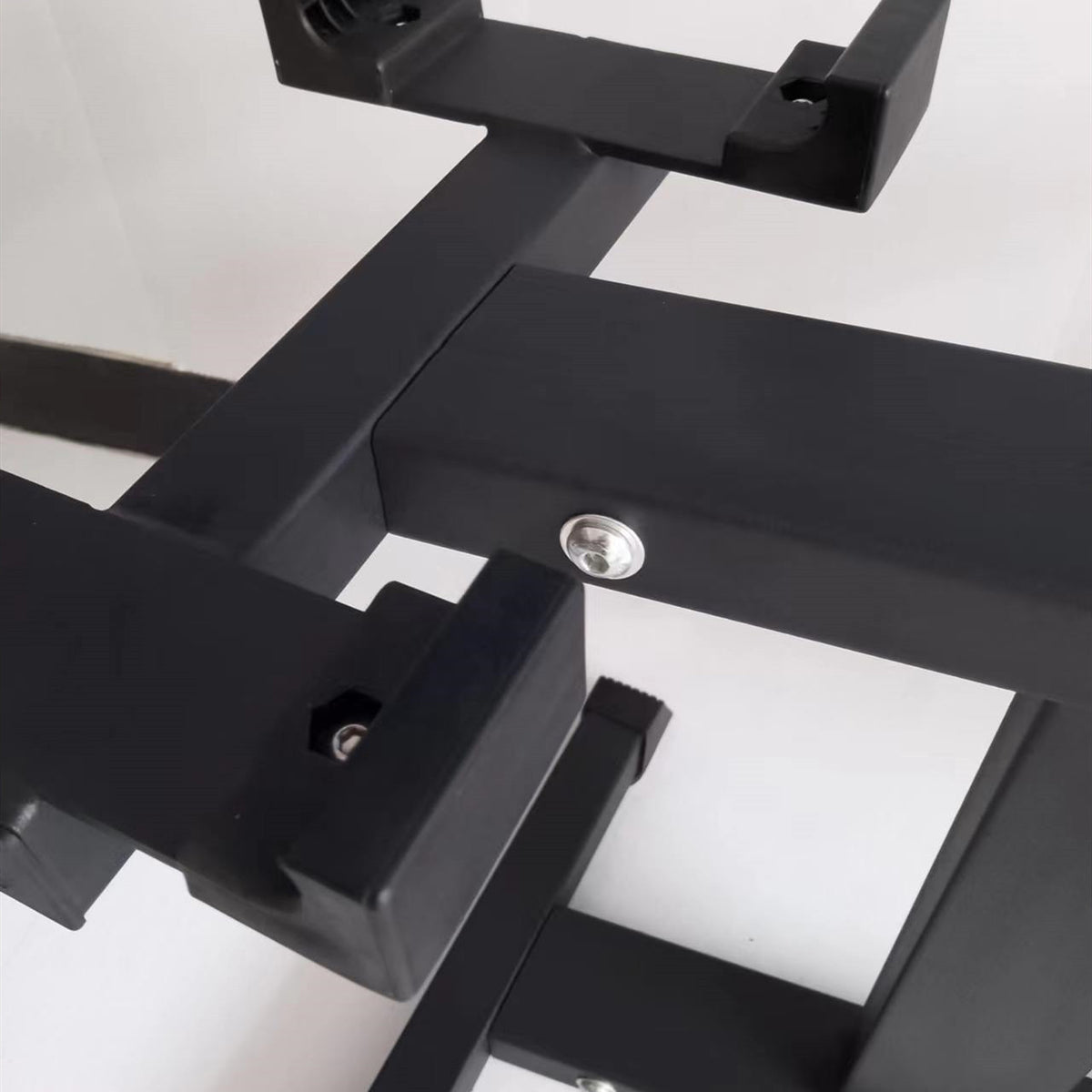 Close-up of a dumbbell cradle bolted to the black steel frame