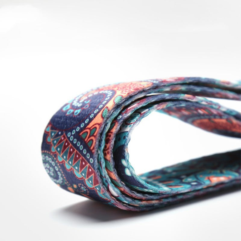 Close-up of a folded printed yoga strap in teal and coral
