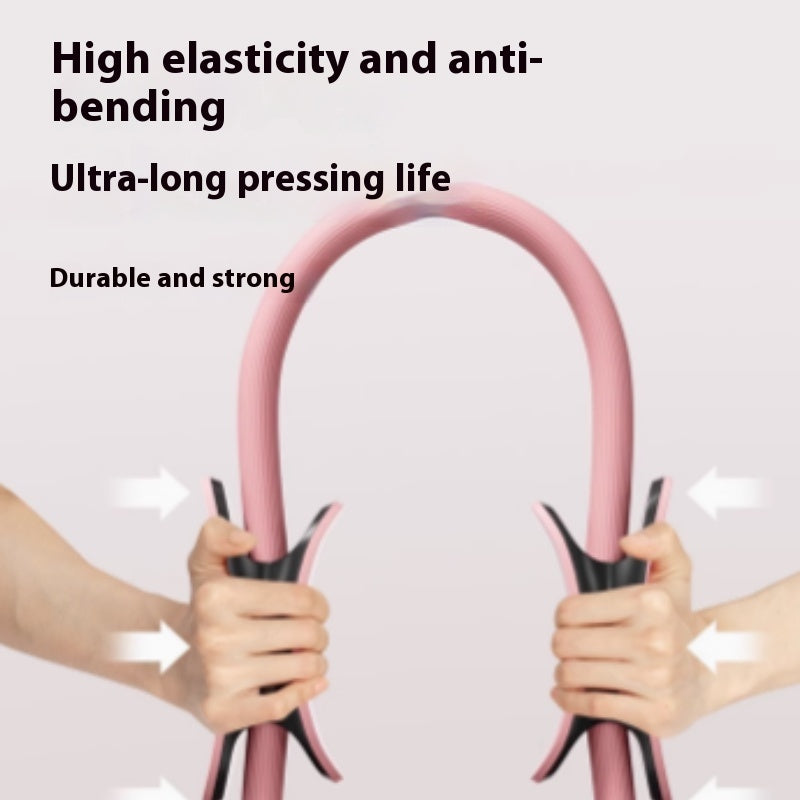 Two hands pressing in on the padded handles of a pink Pilates ring