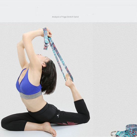 Woman in a kneeling backbend using a printed yoga strap to reach her back foot