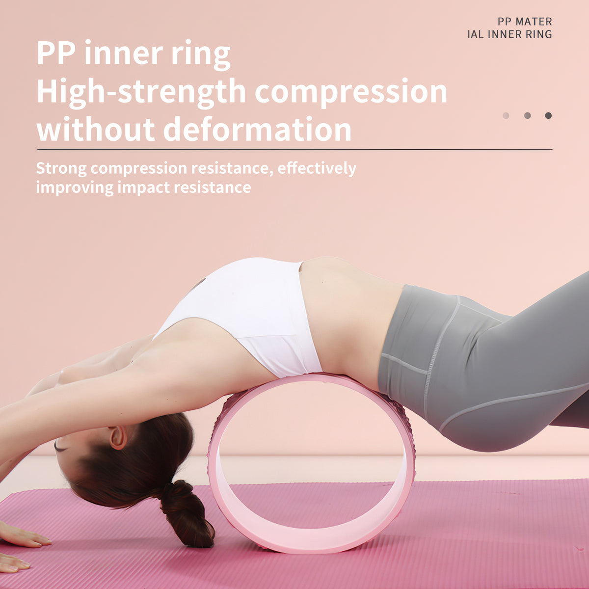 Woman in a backbend with her back arched over a pink yoga wheel