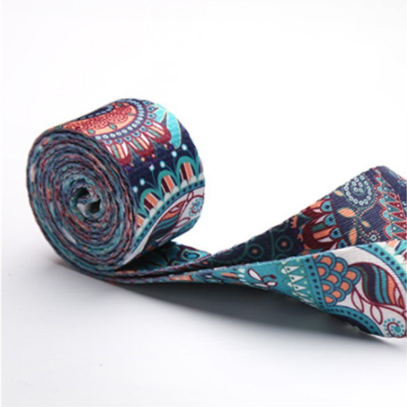 Printed yoga strap partly rolled up, showing its teal and coral pattern