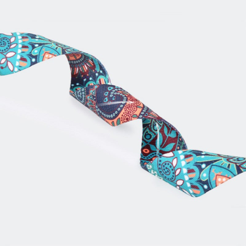 Printed yoga strap twisted to show its teal, navy and coral pattern